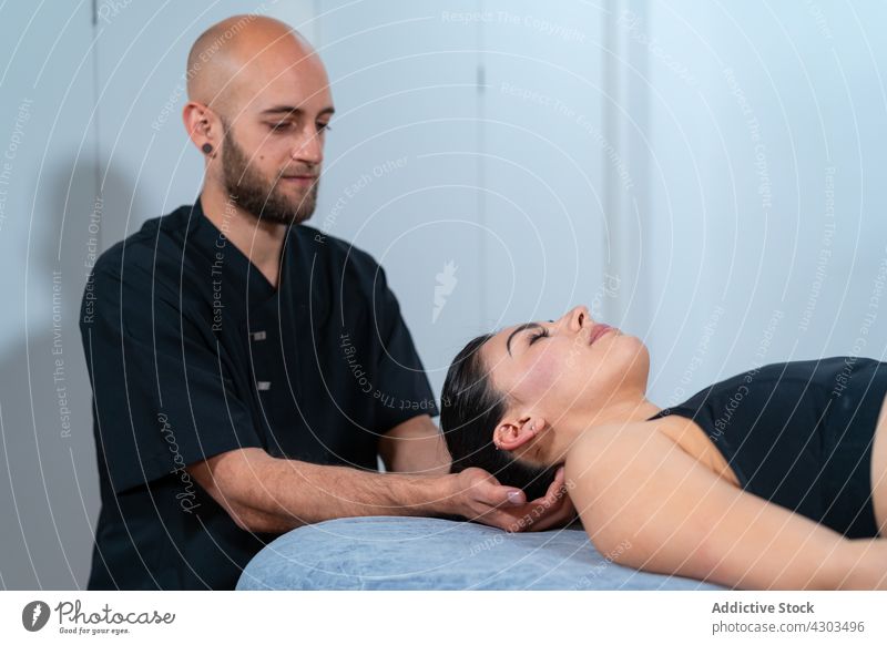 Physiotherapeutin untersucht den Hals eines Patienten in der Klinik Arzt untersuchen geduldig Augen geschlossen Massage Rehabilitation Arbeit Mann Frau