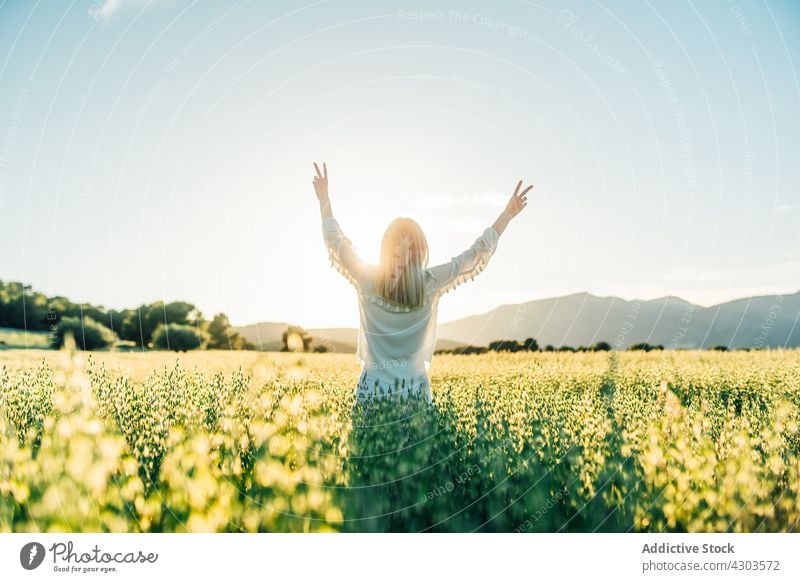 Glückliche Frau zeigt V singen auf dem Lande Feld Freiheit zwei Finger Frieden Natur Landschaft v-Zeichen weißes Kleid Hippie Stil Blume ruhig Windstille