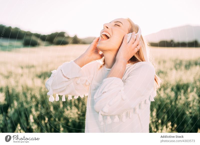 Glückliche Frau, die im Sommer in der Natur mit Kopfhörern Musik hört aufgeregt Freiheit zuhören Feld Landschaft Augen geschlossen heiter sorgenfrei