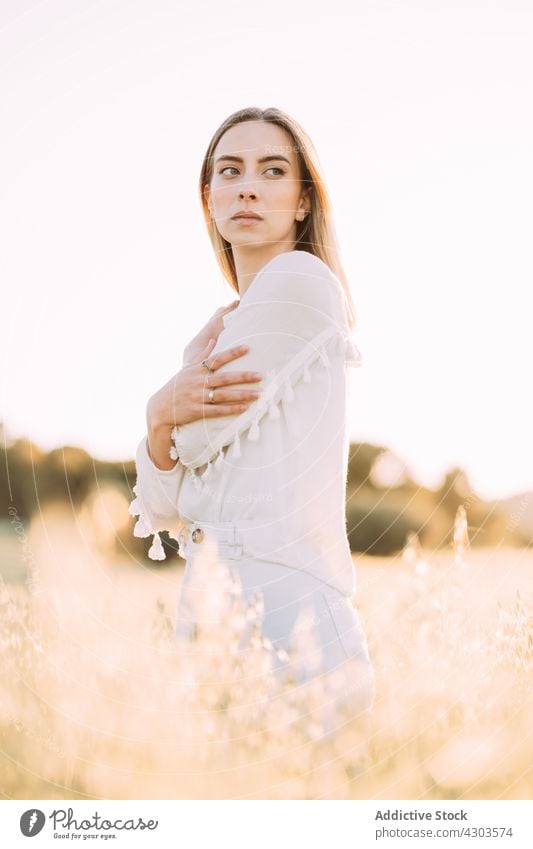 Nachdenkliche Frau im weißen Kleid auf einem sonnigen Feld auf dem Land Gras Sonnenuntergang weißes Kleid romantisch Harmonie Landschaft Freiheit Saison Angebot