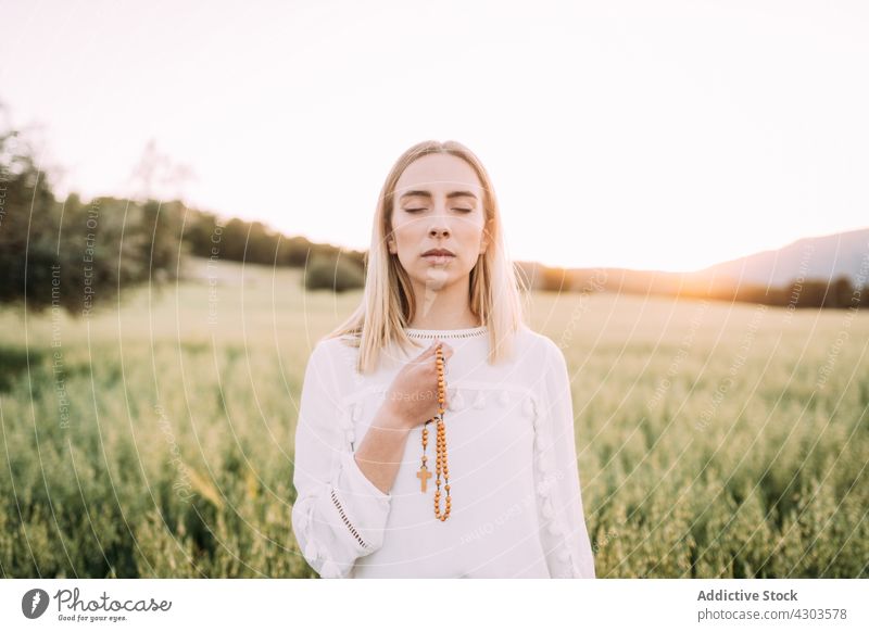 Ruhig betende Frau mit Kreuz im Feld Natur Windstille durchkreuzen Glaube Harmonie Frieden ruhig Religion Wunsch Gelassenheit Wiese ländlich rein weißes Kleid
