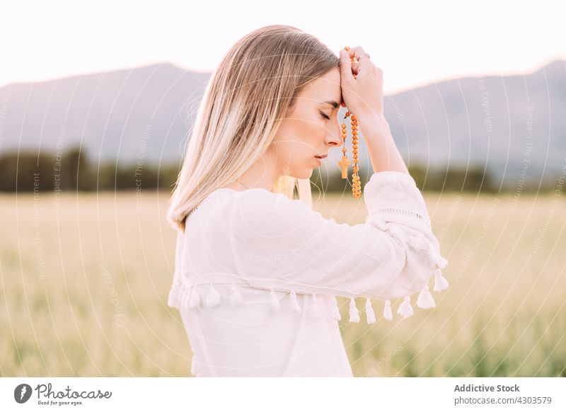 Ruhig betende Frau mit Kreuz im Feld Natur Windstille durchkreuzen Glaube Harmonie Frieden ruhig Religion Wunsch Gelassenheit Wiese ländlich rein weißes Kleid