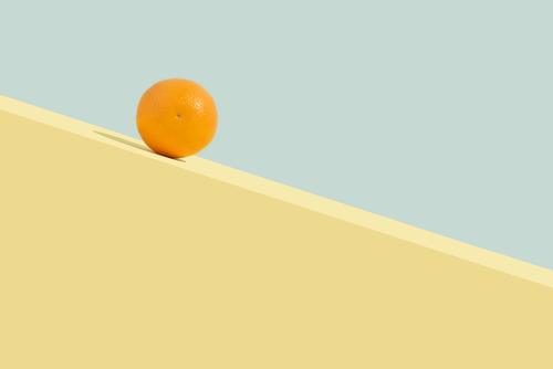 Sommerliche Orangenfrucht, die bergab rollt. Abstraktes Konzept abstrakt Zeitgenosse Rechteck Ästhetik Kunst Hintergrund blau Zitrusfrüchte Farbe farbenfroh