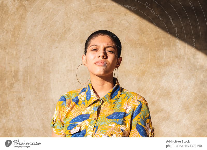 Ethnische Frau im Hemd mit Blumenornament im Sonnenlicht bisexuell geblümt Ornament Geschlecht Identität cool Individualität eitel Porträt Schatten nachdenken