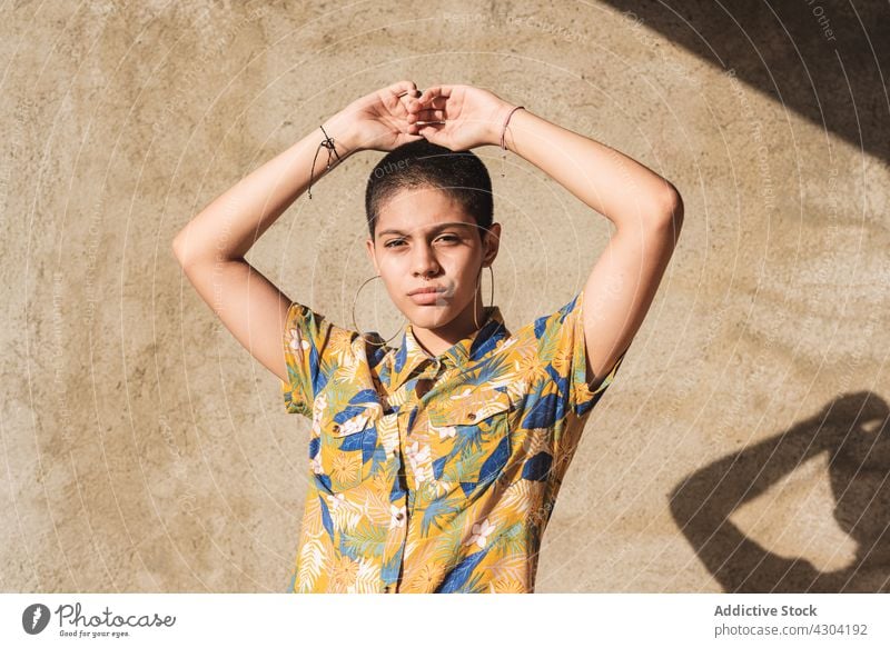 Ethnische Frau im Hemd mit Blumenornament im Sonnenlicht bisexuell geblümt Ornament Geschlecht Identität cool Individualität eitel Porträt Schatten nachdenken