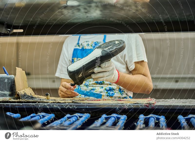 Detail eines Arbeiters, der in einer Fertigungsstraße Klebstoff auf die Schuhsohle aufträgt Herstellung Fabrik Schuhe Schuhfabrik Qualität arbeiten