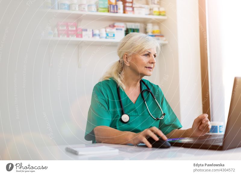 Senior weiblichen Arzt mit Laptop in ihrem Büro Allgemeinmedizinerin gp arzt Gesundheitswesen Medizin Frau eine Person reif älter Tag Kaukasier graues Haar