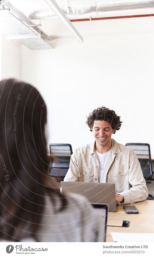 Junges Paar mit Laptops an Schreibtischen bei der Arbeit an einem Start-up-Unternehmen in einem gemieteten Großraumbüro Frau Mann jung Büro Sitzung informell
