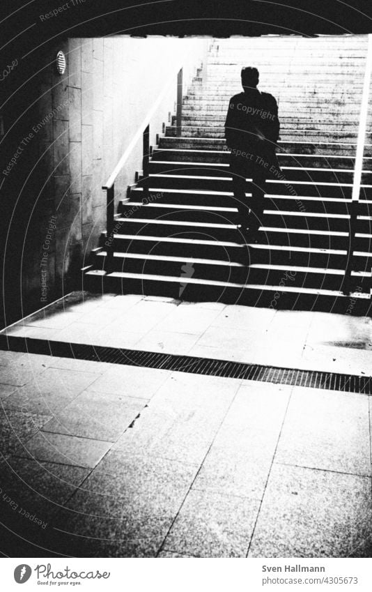Mann steigt eine Treppe hinauf Treppenhaus schwarz-weiß Abstieg Schritt dunkel Treppenstufen taumeln Beine Altstadt Metall Gitterrost Metallgeländer diagonal