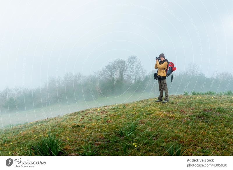 Unerkennbare reisende Frau, die das Hochland fotografiert Reisender fotografieren Berge u. Gebirge Abenteuer Fotograf Nebel Fotoapparat Fotografie Feld Wiese