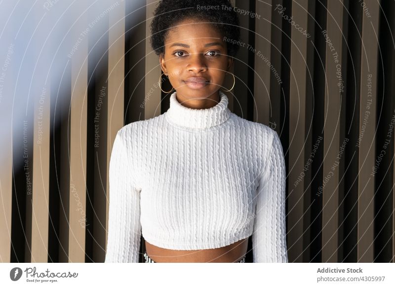 Junge Afroamerikanerin in der Nähe einer gestreiften Hauswand Frau Stil Wand Outfit modern urban Großstadt Straße lässig Porträt Vorschein Mode Model
