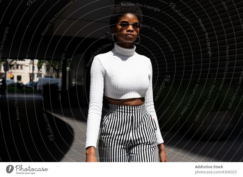 Trendige afroamerikanische Frau mit Sonnenbrille Stil Straße Großstadt modern sonnig tagsüber urban schlendern trendy Stadt Vorschein Outfit Mode jung ethnisch