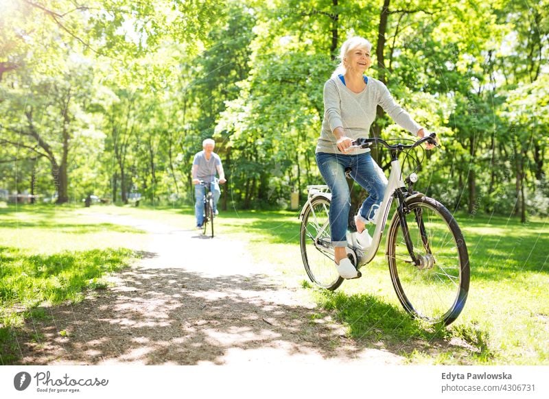 Senior Paar Reiten Fahrräder im Park Fahrrad Zyklus Senioren Rentnerin Rentnerinnen lässig im Freien Tag Kaukasier Fröhlichkeit zahnfarben Lächeln genießend