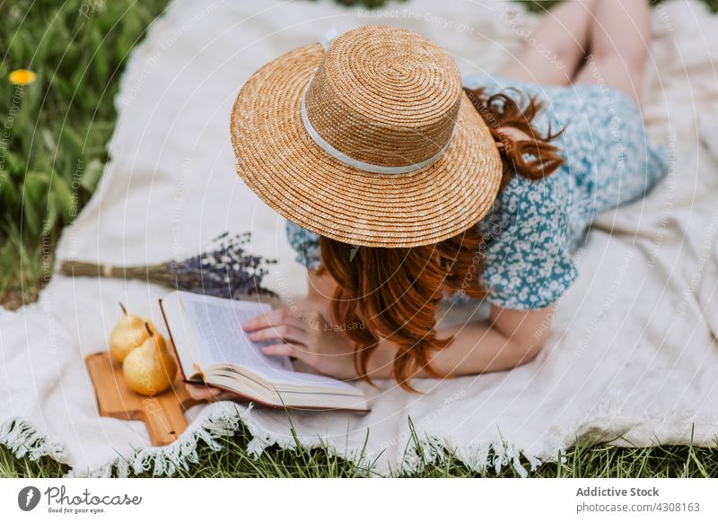 Entspannte Frau mit Buch in sommerlicher Natur ausruhen Picknick sich[Akk] entspannen Sommer Kälte Strohhut Wochenende Decke Landschaft Freizeit Literatur