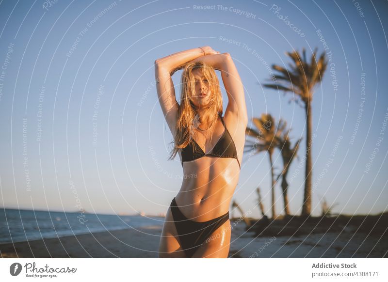 Junge Frau steht am Strand an einem sonnigen Tag Bräune Menschen heiter Sonnenbräune Körper Urlaub blond schön Meer jung MEER Wasser Spaß entspannend Accessoire