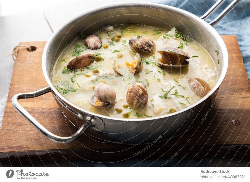 Kochtopf mit Meeresfrüchtesuppe in der Küche Suppe Holzplatte Mahlzeit lecker Lebensmittel Mittagessen geschmackvoll Speise Seehecht Fisch Muschel Kraut Erbse
