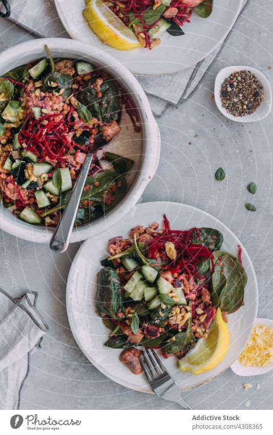 Leckerer Linsensalat auf grauem Tisch Salatbeilage Lebensmittel Gesundheit Serviette Salatgurke Spinat frisch Speise Bestandteil organisch Mahlzeit