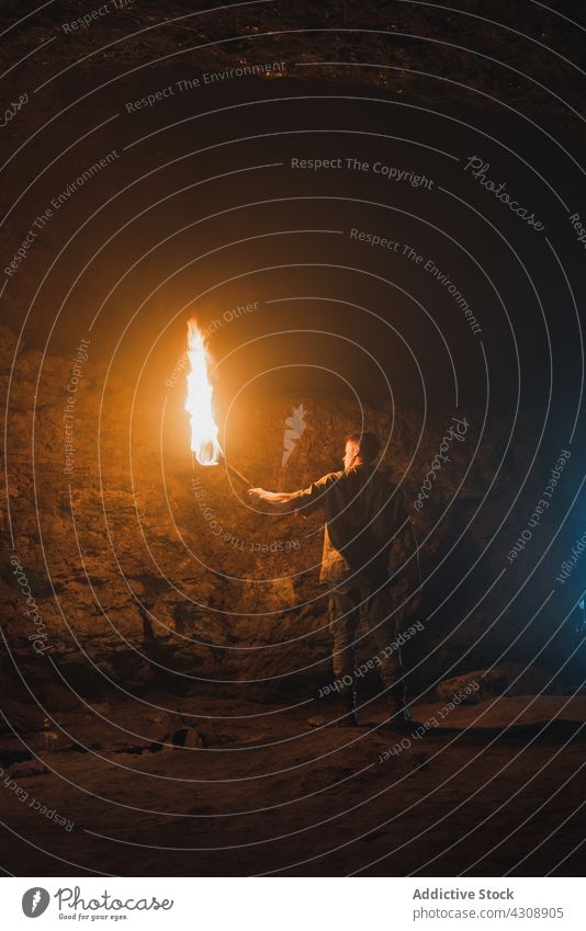 Mann mit brennendem Feuer in dunkler Höhle erkunden Speläologie dunkel Abenteuer felsig Natur Geologie männlich Fackel Felsen Stein reisen Tourismus