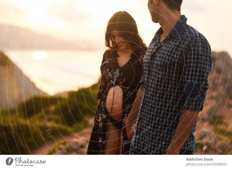 Liebevolle junge Eltern, die am Meer ein Baby erwarten Paar schwanger Glück Zusammensein Natur Bauch Meeresufer Partnerschaft romantisch Händchenhalten Lächeln