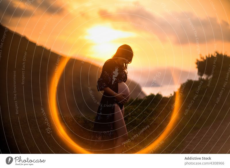 Glückliche schwangere Frau im Sonnenuntergangslicht in der Natur Bauch erwarten Liebe friedlich Mutter mütterlich jung vorwegnehmen Harmonie pränatal