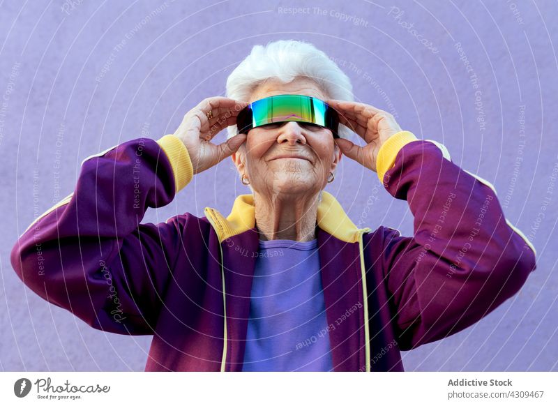 Lächelnde ältere Sportlerin, die ihre Sonnenbrille in die Augenbinde steckt Athlet Mode Stil selbstbewusst Setzen Konzept Frau Porträt blind selbstsicher