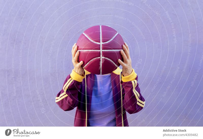 Unbekannter älterer Sportler mit Basketball auf violettem Hintergrund Spieler Deckblatt Gerät Streifen Ornament Kopf Konzept Frau Gesunder Lebensstil