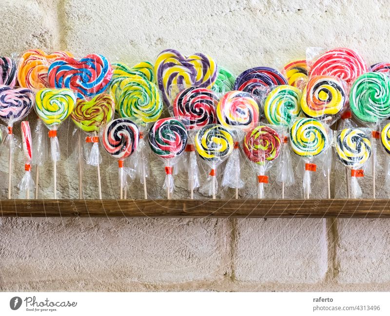 Bunte Spiral-Lollis im Verkaufsregal Lollipop Verwirbelung Bonbon Konditorei süß bunt Spirale gestreift ungesund vereinzelt kleben Saugnapf rot Zucker