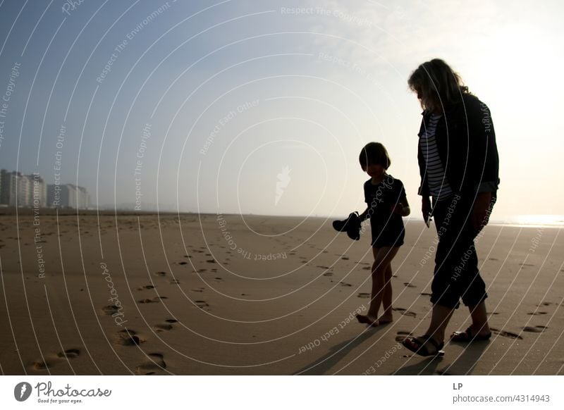 Kontrast Silhouetten eines Kindes und Erwachsenen zu Fuß auf dem Strand Outdoor-Erholung Strukturen & Formen Bildung Spielen Pazifik Meeresstrand Lifestyle
