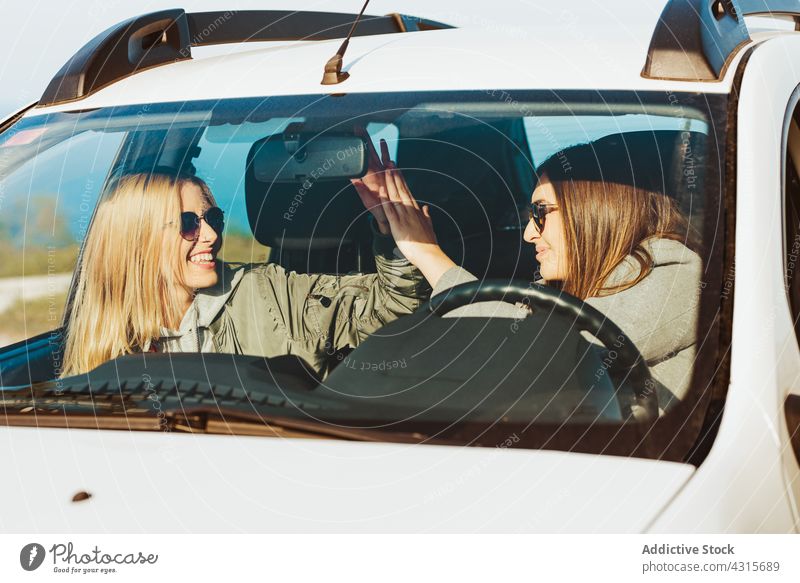 Glückliche Frauen geben High Five im Auto reisen PKW high five Zusammensein Freundschaft heiter Ausflug Verkehr Freiheit Landschaft gestikulieren Fahrzeug Natur