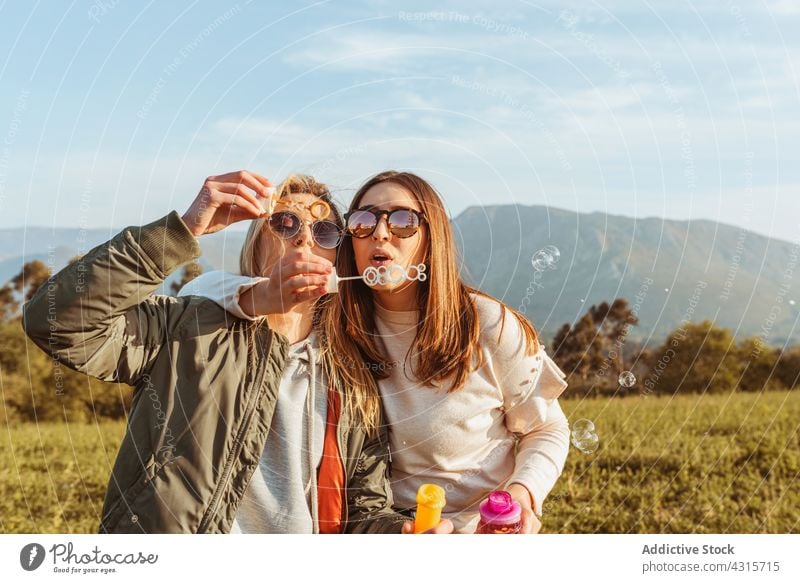 Glückliche Frauen mit Seifenblasen in der Natur Spaß Schlag Zusammensein bester Freund Freundschaft Sommer Sonnenbrille Wiese ruhen Freizeit sorgenfrei Freundin