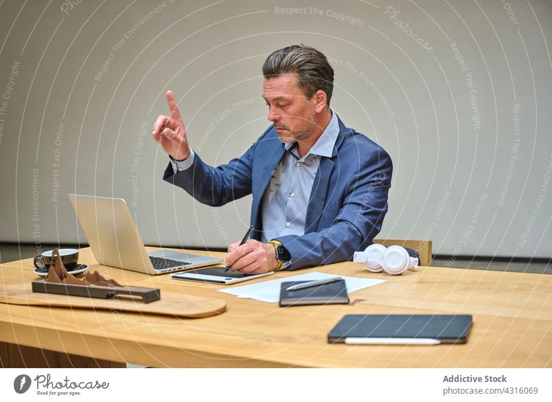 Designer am Schreibtisch in seinem Büro bei der Arbeit an seinem Laptop Mann Coworking Computer Internet Menschen Tisch Dienststelle Smartphone Architekt