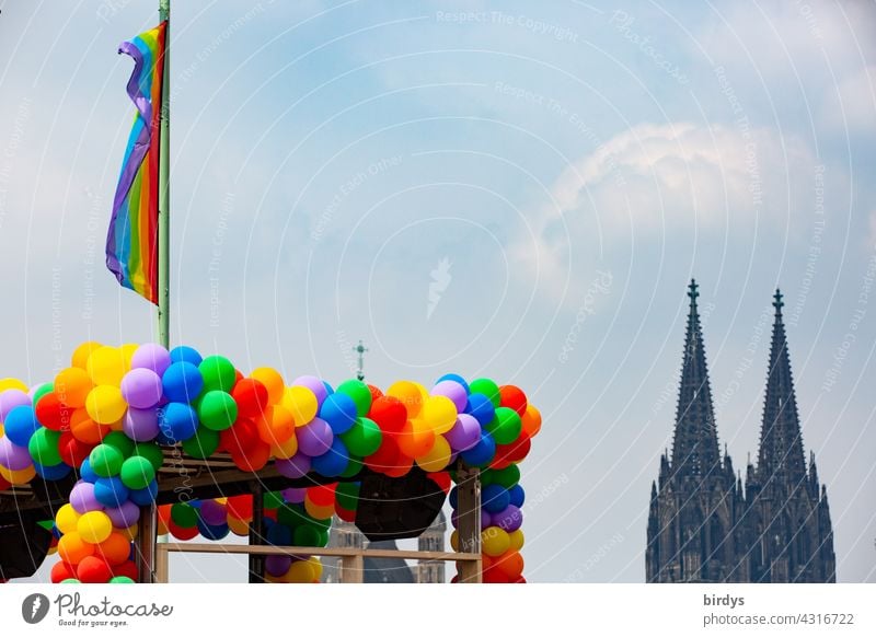 viele bunte Luftballons in Regenbogenfarben und eine Regenbogenflagge vor dem Kölner Dom Regenbogenfahne katholische Kirche Gendergerechtigkeit