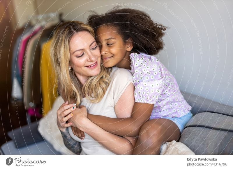 Mutter und Tochter umarmen zu Hause Kind Familie multiethnisch gemischte Rassenfamilie vielfältige Familie Vielfalt Afro-Look heimwärts echte Menschen