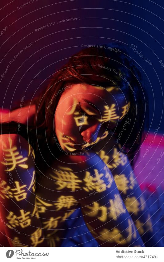 Junge Frau mit Lichtprojektion auf der Haut Projektor Hieroglyphen Orientalisch Kunst Kultur Porträt Stil leuchten Model rot dunkel jung kreativ Vorschein