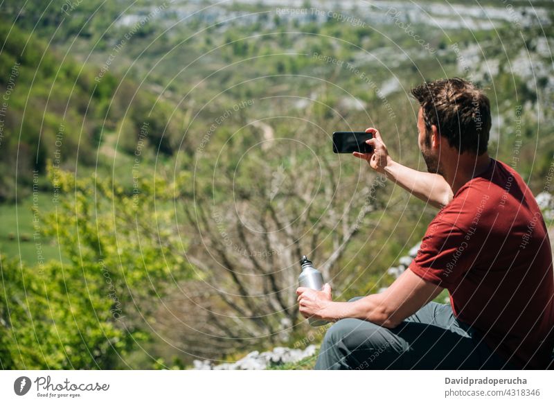 Lächelnder Reisender, der ein Foto mit seinem Smartphone macht, während er sich bei einer Wanderung ausruht Wanderer Trekking benutzend positiv ruhen Hochland