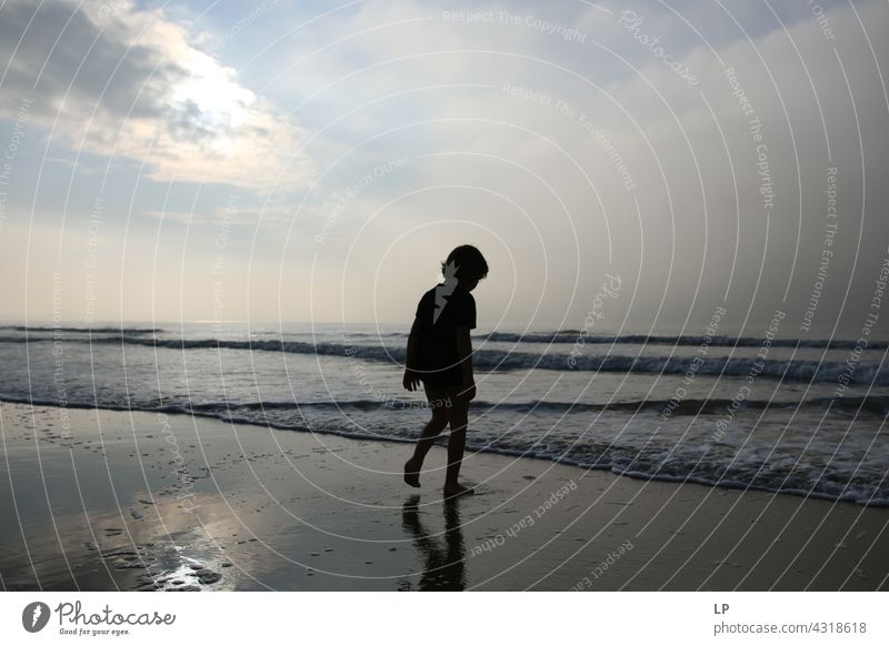 Kontrast Silhouette eines Kindes zu Fuß in Richtung Meer und Himmel Outdoor-Erholung Strukturen & Formen Bildung Spielen Pazifik Meeresstrand Lifestyle stimmig