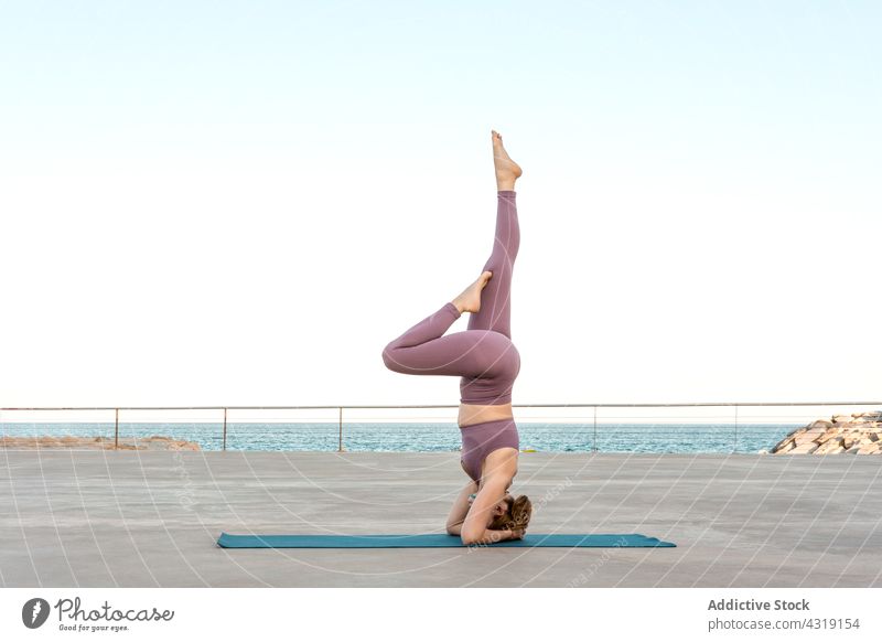 Flexible Frau, die Yoga im unterstützten Kopfstand praktiziert Pose Gleichgewicht Salamba sirsasana Achtsamkeit Zen MEER Strandpromenade Asana üben Wohlbefinden
