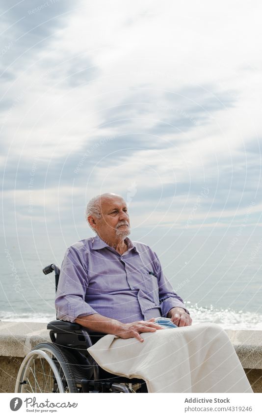 Nachdenklicher Mann im Rollstuhl an einer Böschung Senior Stauanlage MEER älter deaktivieren Handicap alt Spazierweg männlich in den Ruhestand gehen Rentnerin
