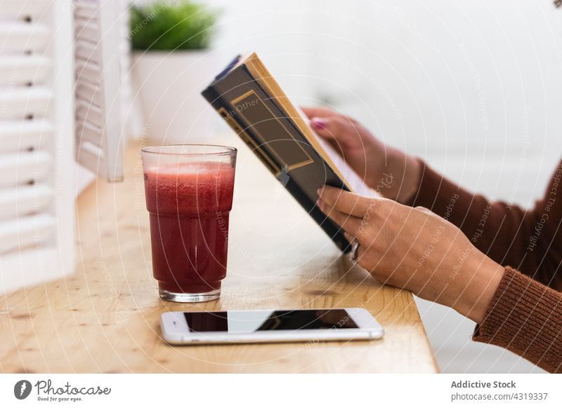 Anonyme afroamerikanische Frau, die in einer Bar einen Smoothie trinkt und ein Buch liest trinken Erfrischung lesen Getränk Sommer Kälte schwarz Afroamerikaner