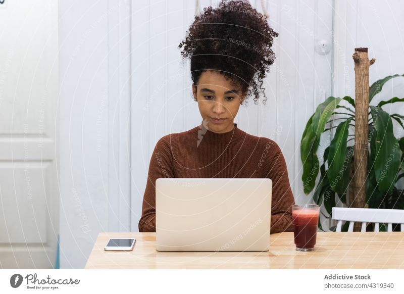 Schwarze Frau arbeitet an einem Laptop in einem Café Arbeit freiberuflich Smoothie Browsen abgelegen benutzend Projekt Afroamerikaner schwarz ethnisch