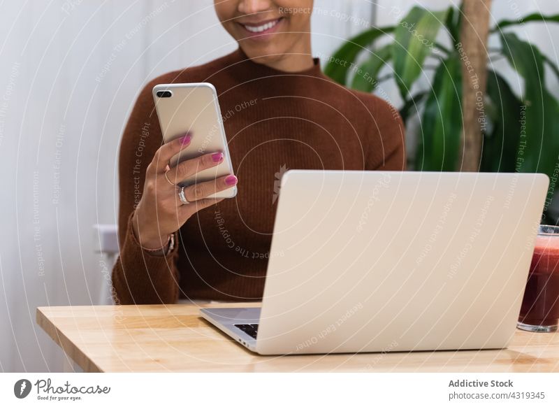 Anonyme zufriedene schwarze Frau arbeitet in einem Café Arbeit freiberuflich Browsen Smartphone benutzend heiter Surfen abgelegen Afroamerikaner ethnisch Tisch