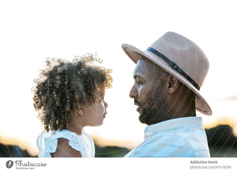 Schwarzer Vater hält süße Tochter bei Sonnenuntergang Kind Zusammensein Eltern Liebe Halt schwarz Afroamerikaner ethnisch Partnerschaft Papa wenig Zuneigung