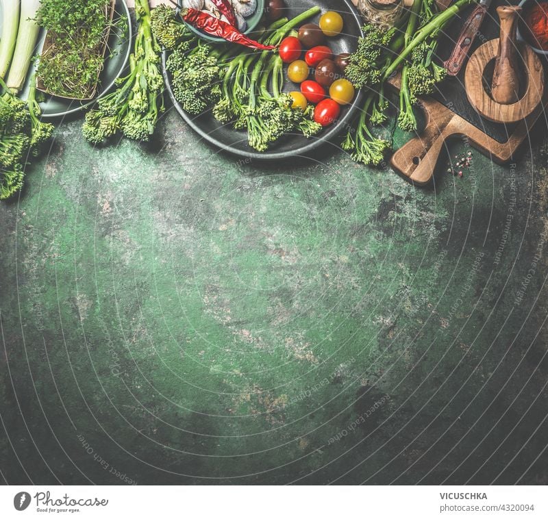 Lebensmittel Hintergrund mit einer Vielzahl von grünem Gemüse, wilden Brokkoli, Tomaten und andere gesunde Zutaten für die vegane Küche. Umrandung. Ansicht von oben