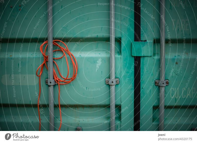 Zwischenräume | Ein orangenes Kabel ist an einem grünen Container eingeklemmt Zwischenraum eingequetscht Übersee Containerschiff Containerterminal