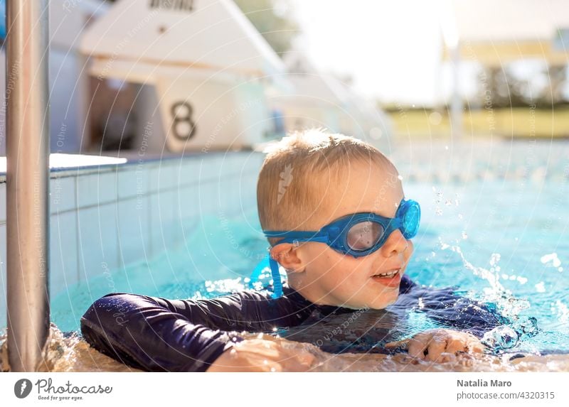 Kind mit Schwimmbrille im Schwimmbad Pool blau Junge Urlaub schwimmen Wasser im Freien Sommer Schutzbrille Glück Freude Lächeln nass Erholung spielen Freizeit