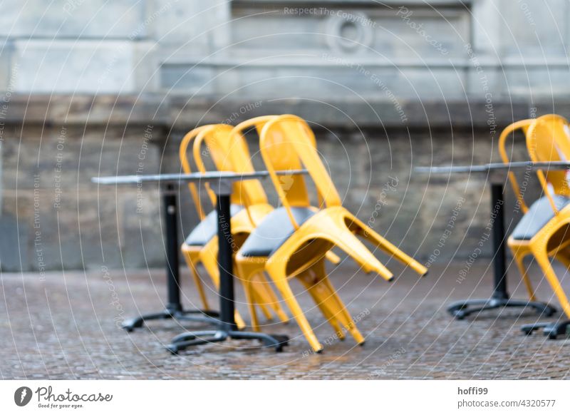 an Tische angelehnte Stühle in einem Straßencafé - Saisonende Bistro geschlossen schlechtes Wetter Herbst Regen Café Terrasse Stuhl leer Gastronomie Biergarten