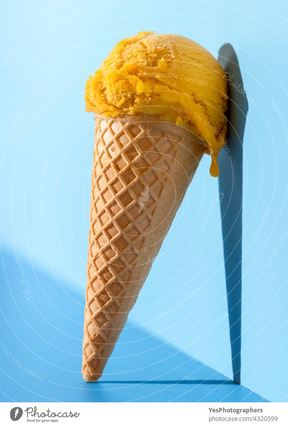 Mango-Eis in hellem Licht, auf einem blauen Hintergrund. Ball Nahaufnahme kalt Farbe Konzept Zapfen Textfreiraum Sahne ausschneiden lecker Dessert Tropf