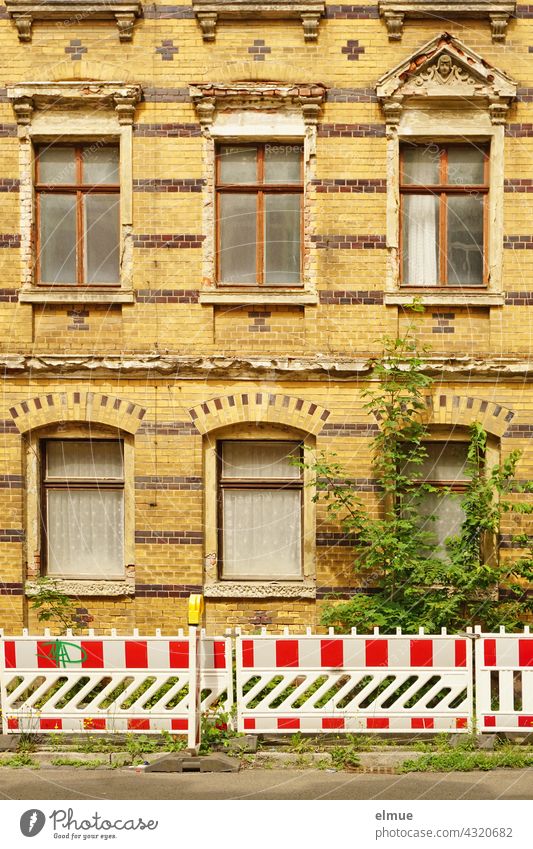 rot-weiße Absperrbaken vor einem reichlich verzierten aber langsam zerfallenden Wohnhaus mit gelb-brauner Klinkerfassade aus der Gründerzeit / marode / Lost Place