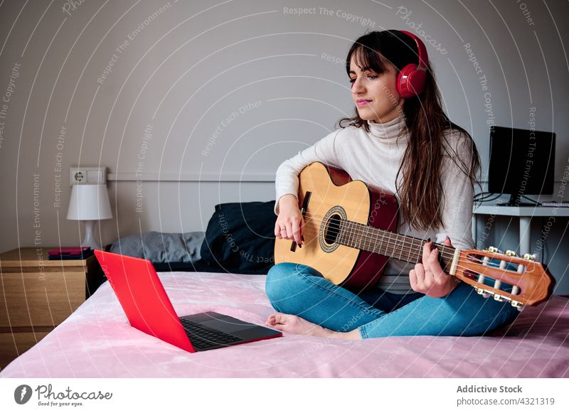 Frau spielt Gitarre und beobachtet Online-Lektion spielen online Sitzung Tutorial Musik Musiker Gitarrenspieler Gesang Melodie Instrument akustisch Laptop