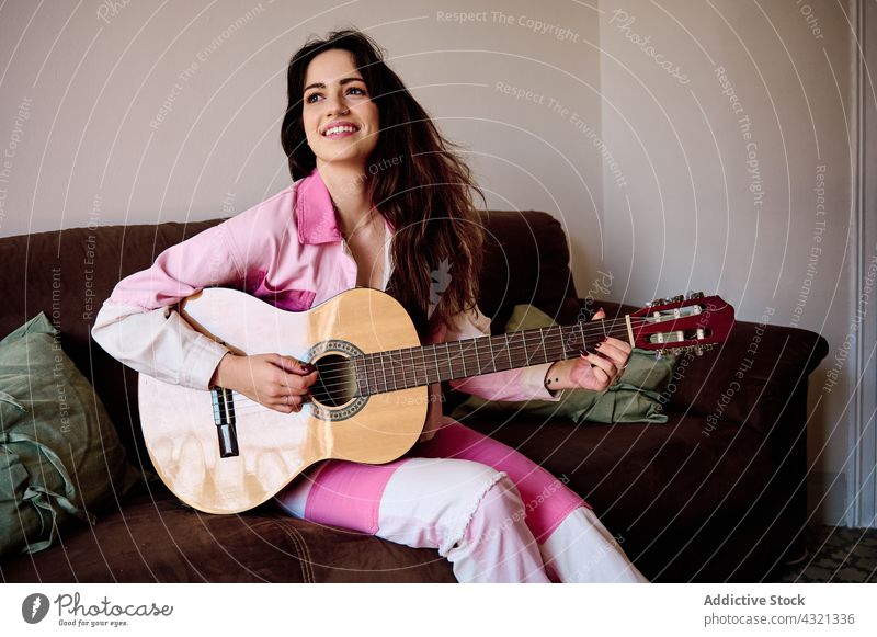 Lächelnde Frau spielt Gitarre zu Hause spielen akustisch Musik Musiker Instrument Melodie Gitarrenspieler genießen Klang Gesang Glück Probe Hobby ausführen